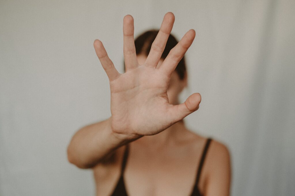 Mujer con la palma de la mano extendida hacia la cámara en un gesto de parar.