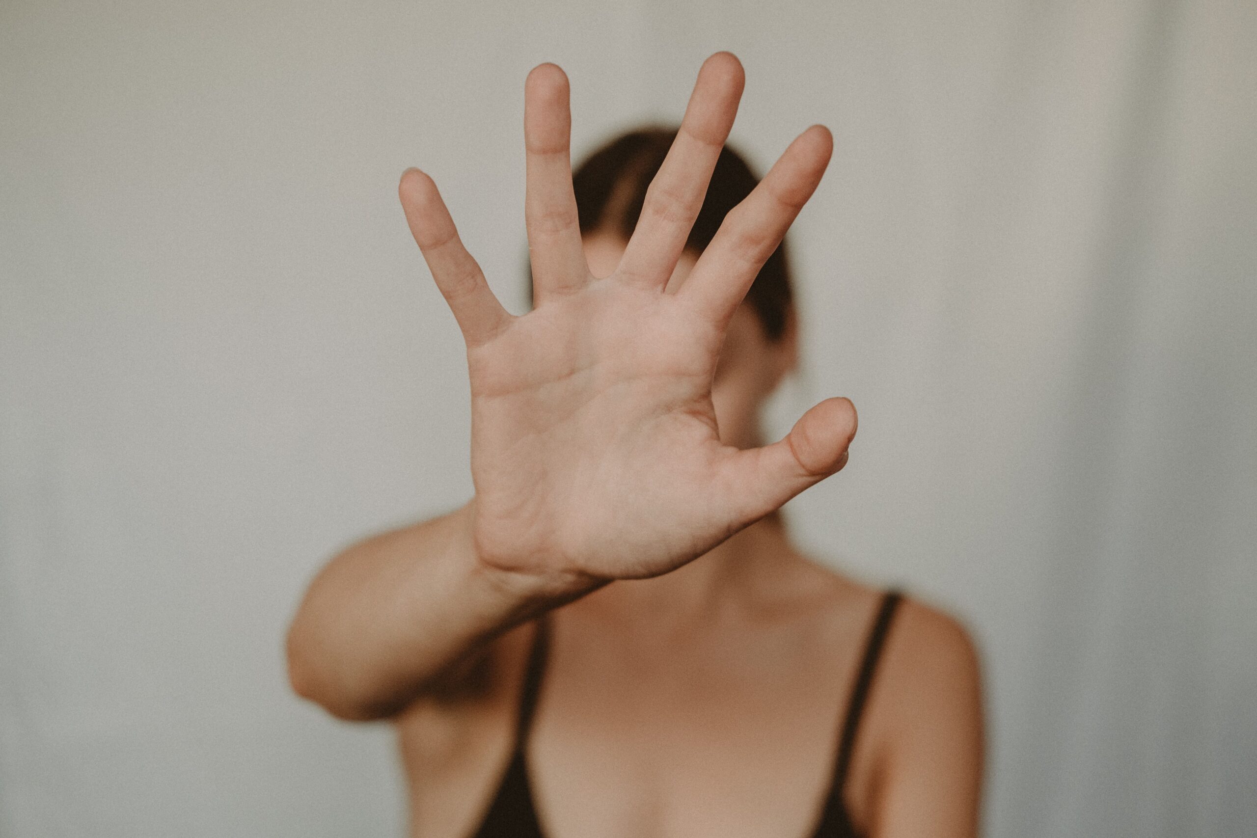 Mujer con la palma de la mano extendida hacia la cámara en un gesto de parar.