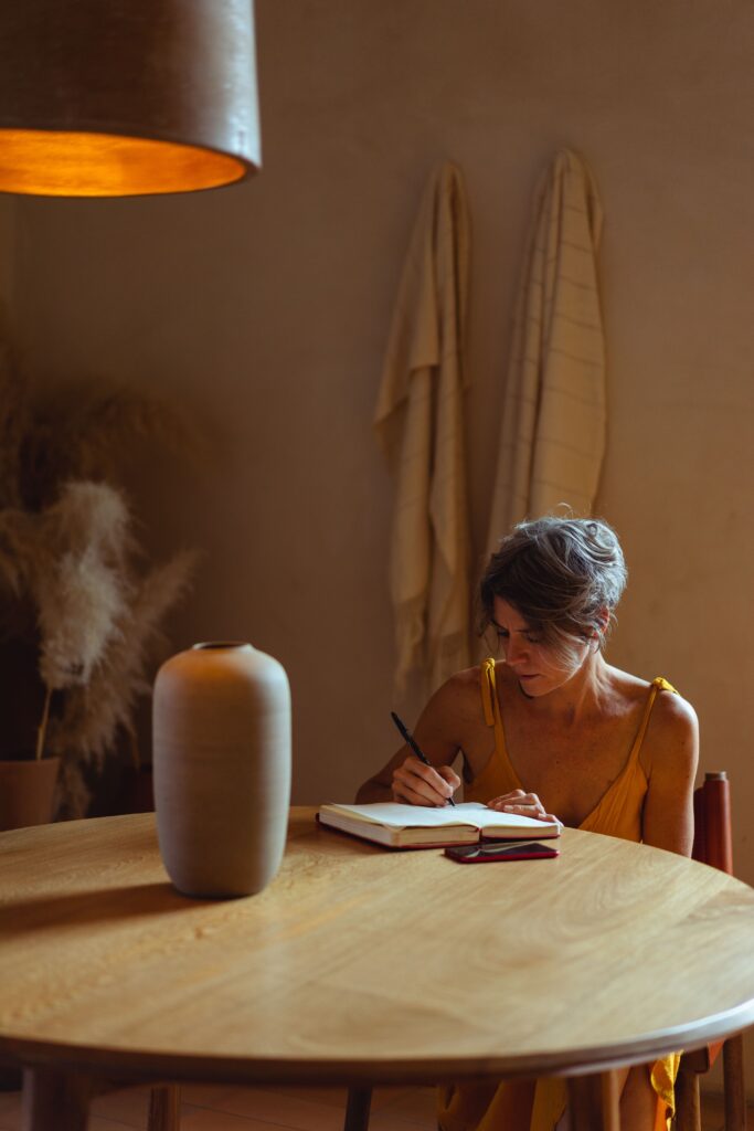 Mujer escribiendo en un cuaderno abierto sobre una mesa de madera