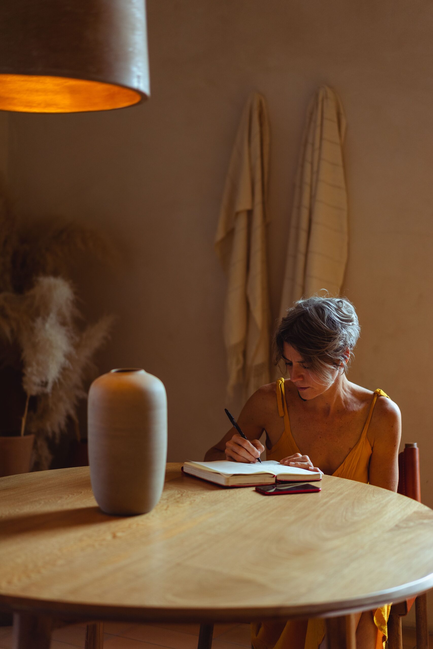 Mujer escribiendo en un cuaderno abierto sobre una mesa de madera